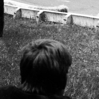 Vintage race car driving on winding road with spectators.