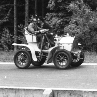 Vintage car race with onlooker near road.