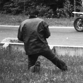 Vintage car race with onlooker near road.