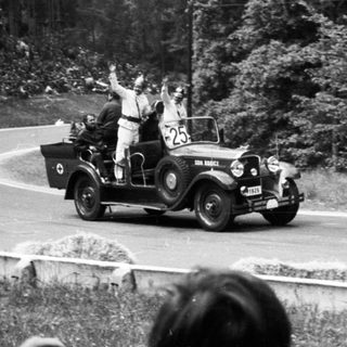 Vintage car race with cheering spectators.