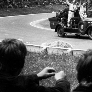 Vintage car race with cheering spectators.