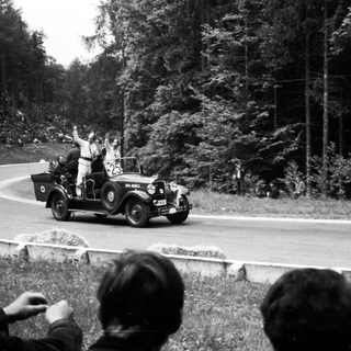 Vintage car race with cheering spectators.