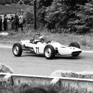 Classic race car on curved roadway during vintage motorsport event.