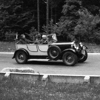 Classic vintage car race on rural road.