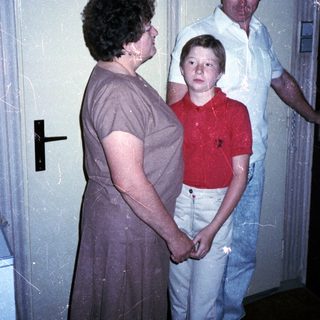 Family members standing indoors near a door.