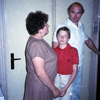 Family members standing indoors near a door.