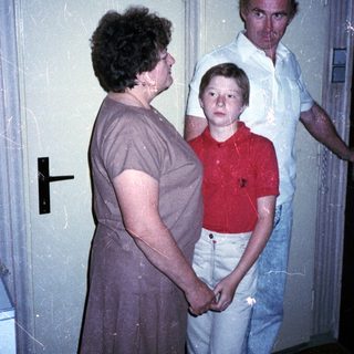 Family members standing indoors near a door.