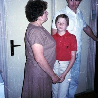 Family members standing indoors near a door.