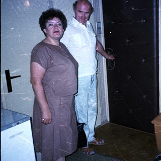 Three people in a dimly lit room, one sitting, others standing.