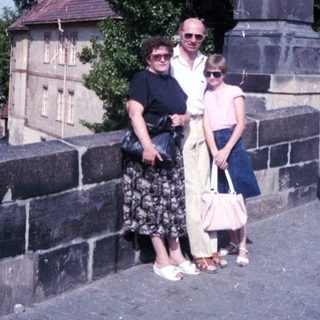 Family posing near historic statue on bridge.