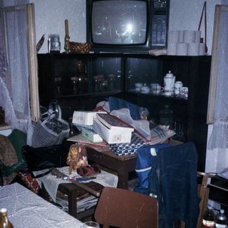 Cluttered room with old TV, table, and miscellaneous items.