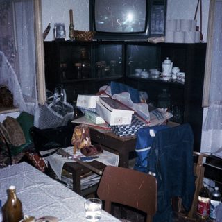 Cluttered room with old TV, table, and miscellaneous items.