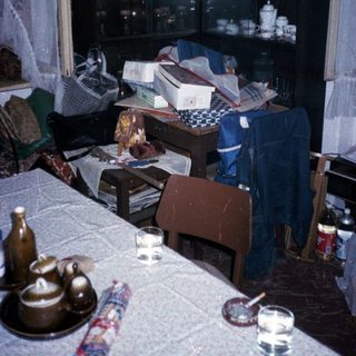 Cluttered room with old TV, table, and miscellaneous items.