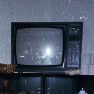 Cluttered room with old TV, table, and miscellaneous items.