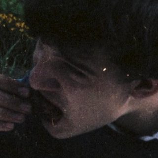 Man eating cake outdoors by a table.