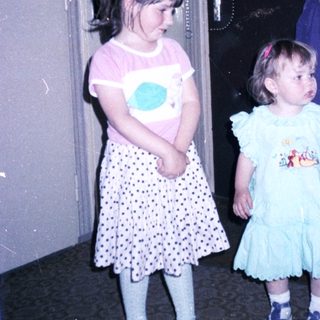 Two young girls with an adult in doorway.