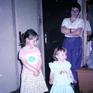 Two young girls with an adult in doorway.