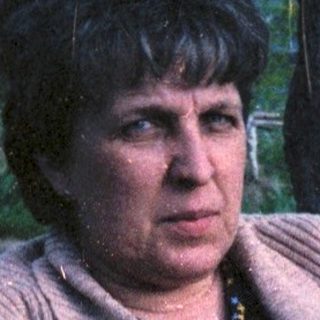 Woman sitting alone outdoors near water.