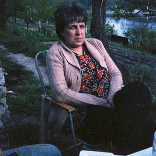Woman sitting alone outdoors near water.
