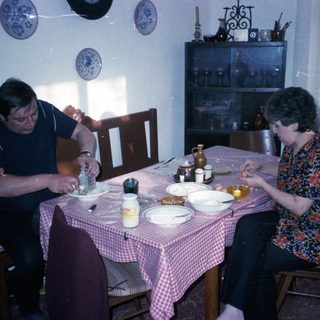 Two people eating breakfast at a vintage table.