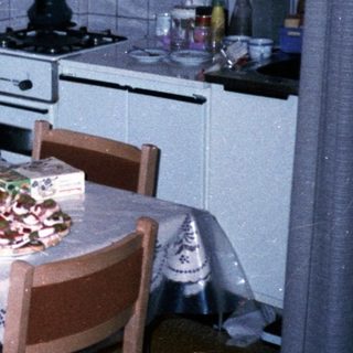 Woman sitting at kitchen table with flowers and food.