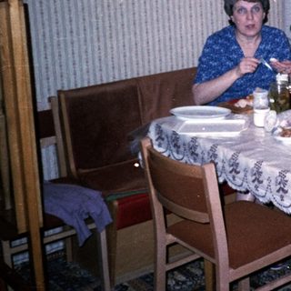 Woman sitting at kitchen table with flowers and food.