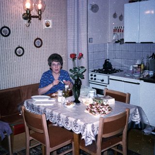 Woman sitting at kitchen table with flowers and food.