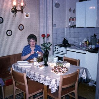 Woman sitting at kitchen table with flowers and food.