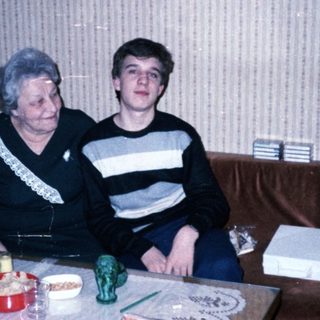 Two people sitting indoors, posing together on a couch.