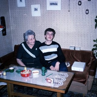 Two people sitting indoors, posing together on a couch.