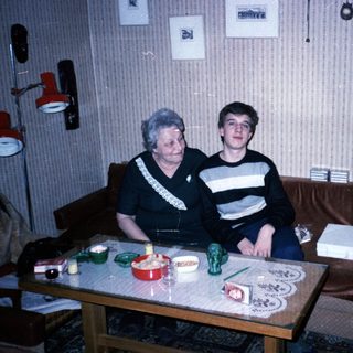 Two people sitting indoors, posing together on a couch.