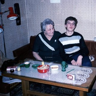 Two people sitting indoors, posing together on a couch.