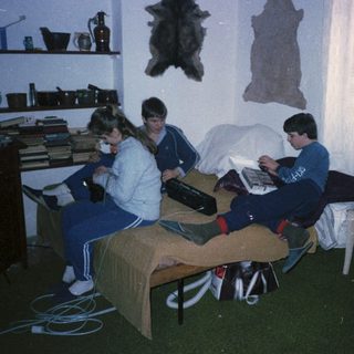 Three people studying together in a dorm room.
