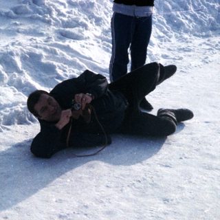 Person lying in snow, another standing nearby.