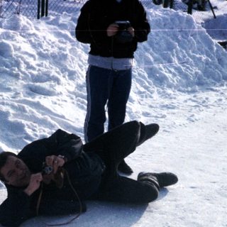 Person lying in snow, another standing nearby.