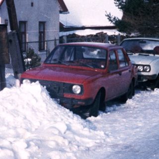 Snow-covered residential street with parked cars.