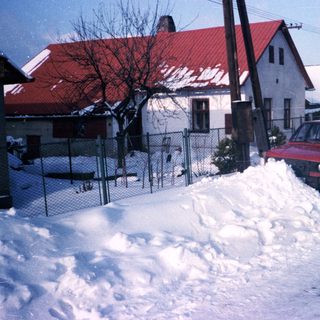 Snow-covered residential street with parked cars.