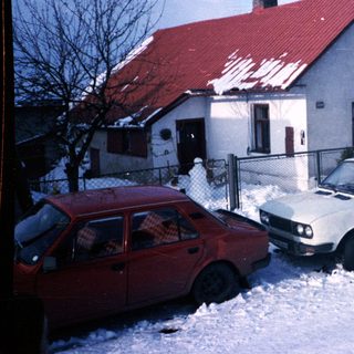 Snowy residential street with two parked cars.