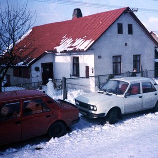 Snowy residential street with two parked cars.