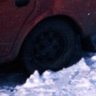 Snowy residential street with two parked cars.