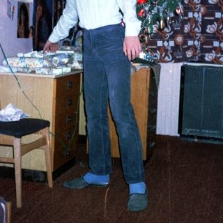 Young man standing by decorated Christmas tree in living room.