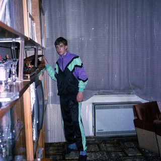 Person in overalls and gloves organizing refrigerator shelves.