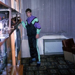 Person in overalls and gloves organizing refrigerator shelves.