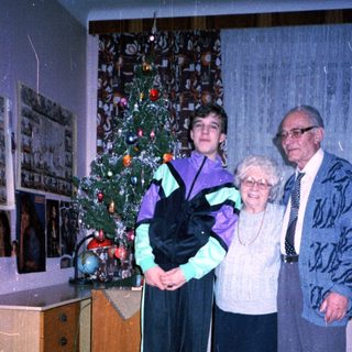 Family posing with Christmas tree indoors.