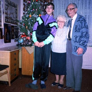 Family posing with Christmas tree indoors.