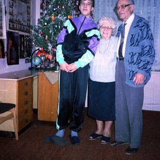 Family posing with Christmas tree indoors.