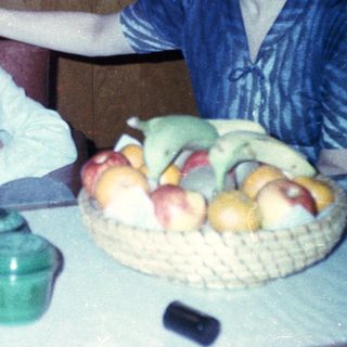 Family moment with child and adult indoors near fruit bowl.