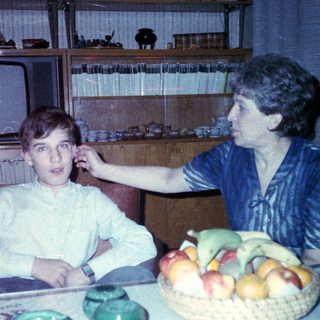 Family moment with child and adult indoors near fruit bowl.