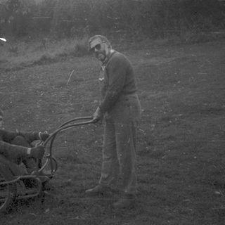 Two men in grassy field with manual wheelchair.