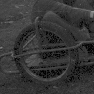 Two men in grassy field with manual wheelchair.